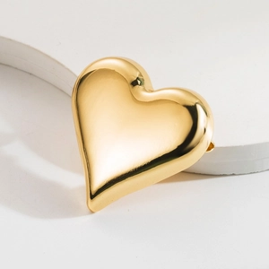 Polished gold heart brooch with a minimalist 3D metal design on aesthetic stone background