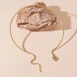 Gros plan sur le collier serpent doré orné de diamants sur un support en roche naturelle