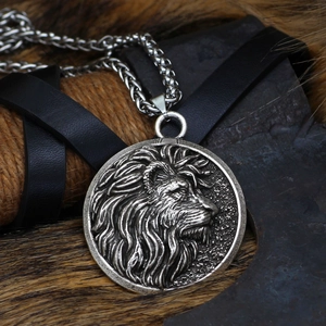 Close-up of a silver lion head pendant with a thick twisted chain on a rustic background
