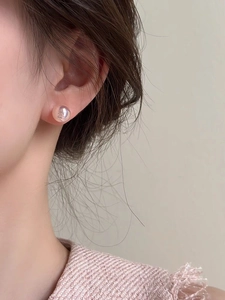 Close-up of pink mermaid pearl stud earrings with aurora luster on model's ear