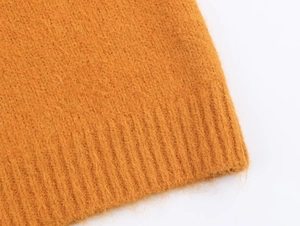 Vue détaillée de la texture maille côtelée douce sur l'ourlet du pull en tricot orange