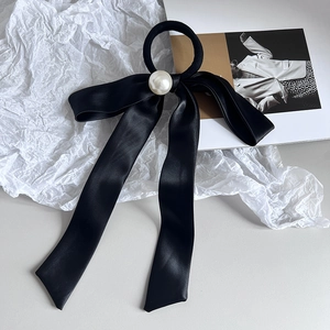 Elegant black satin bow hair tie with large white pearl on minimalist white background