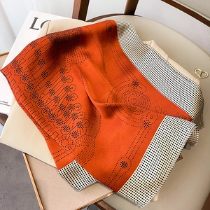 Detailed shot of an elegant orange polka dot silk scarf draped over beige fabric