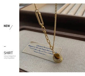 Macro detail of sun-shaped tiger eye stone pendant with asymmetric paperclip chain link