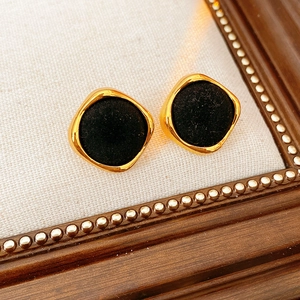 Gros plan de boucles d'oreilles vintage carrées avec monture dorée et flocage noir