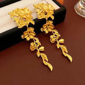 Détail de boucles d'oreilles fleuries en or mat avec feuilles sur une boîte à bijoux