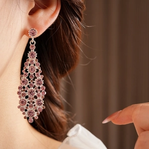 Detalle de pendientes de borla plateados con circonitas rosas en una modelo real