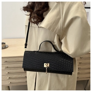 Detail of black woven shoulder bag with gold buckle on a model wearing a beige coat