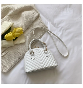 Macro detail of white quilted shell bag with golden hardware and floral decor