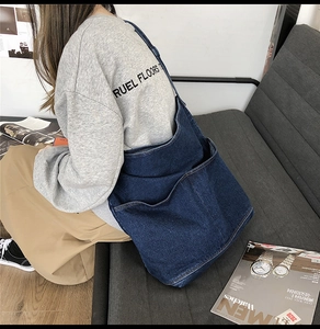 Detail of a large dark blue denim shoulder bag with white contrast stitching on a sofa