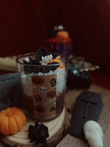 Detail showing a Halloween soy candle with bat and pumpkin wax toppers in a glass cup