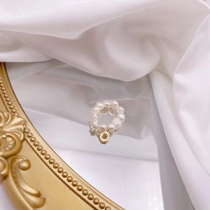 Macro detail of French vintage freshwater pearl ring with gold circular pendant on a mirror