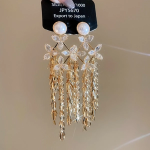 Macro detail of 18K gold plated flower tassel earrings with crystals and white pearls