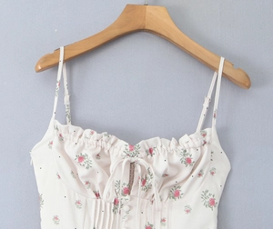 Detailed view of floral strap dress with lace trim and bow knot on wooden hanger