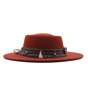 Detail of rust red wide brim boater hat with bohemian ethnic ribbon and colorful beads