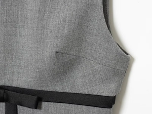 Close-up of the grey fabric texture with a black satin bow on the sleeveless dress