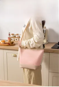 Pink and beige insulated lunch bag with shoulder strap shown in a home kitchen setting