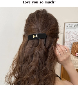 Detail view of retro acrylic hair clip with gold H logo on a vintage style model