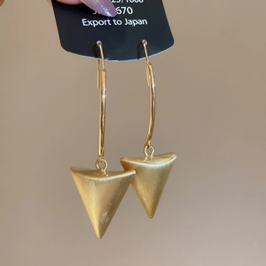 Macro shot of brushed 18k gold plated triangle earrings with elegant matte texture