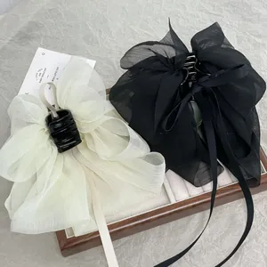 Detail view of large chiffon bow hair claws in cream and black with elegant long ribbons
