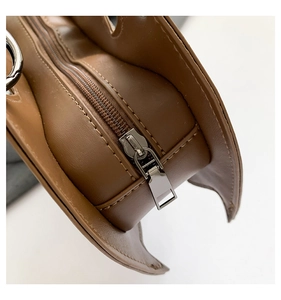 Close-up detail of smooth brown synthetic leather texture and silver zipper on the bat bag