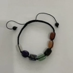 Detail of adjustable Seven Chakra natural stone bracelet with colorful beads and black cord