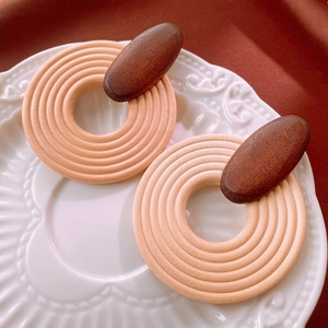 Close-up of bohemian round wooden earrings with natural grain on a textured white plate