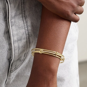 Detailed view of three-piece gold-plated zircon bangles worn on a model's wrist