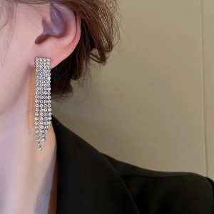 Dettaglio di orecchini a frangia argentati con strass indossati da una modella