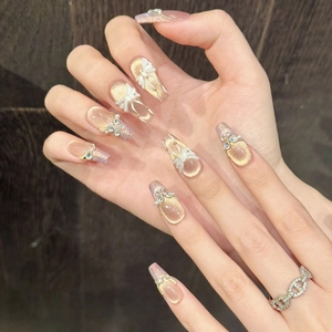 Detail of handmade bow press-on nails with 3D pearls and champagne cat-eye glitter finish