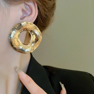 Gros plan de boucles d'oreilles rondes dorées avec texture de métal martelé sur modèle