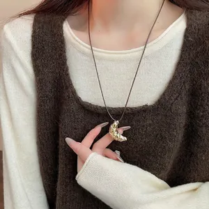 French retro croissant pendant necklace with brown leather cord on white sweater