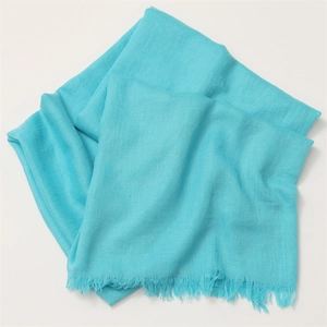 Detail of turquoise linen scarf featuring soft texture and delicate fringe edges