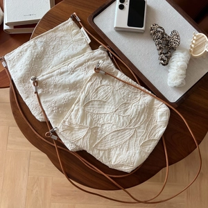 Detailed view of three beige cotton linen crossbody bags with exquisite floral embroidery