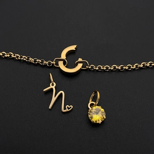 Detail van gouden titanium staal letter hanger en gele zirkoon voor DIY sieraden