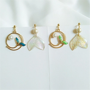 Detailed view of asymmetric mermaid tail earrings with pearls and blue enamel finish