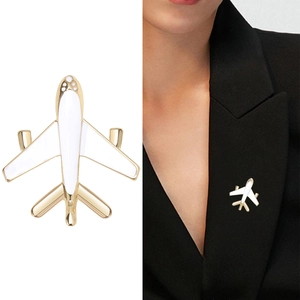 Minimalist gold airplane enamel brooch pin with small diamonds shown on a black suit lapel