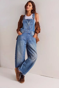 Detail of vintage washed blue denim overalls with large front pocket and loose straight fit