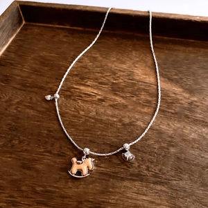 Détail d'un collier réglable argenté avec pendentif cheval en bois et coeur