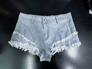 Dettaglio di pantaloncini di denim a vita alta azzurro con orlo a frange e trama del denim