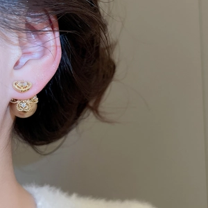 Macro side view of vintage crown pearl earrings featuring golden front-back design