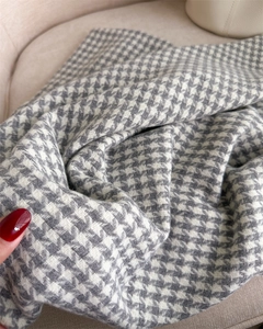 Macro detail of houndstooth scarf fabric texture being held to show softness and drape
