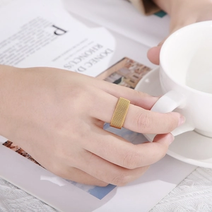 Macro shot of wide gold mesh woven ring texture on finger holding coffee cup