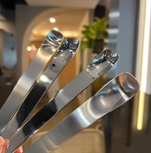 Close-up of four polished stainless steel dessert spoons with a brushed metal finish