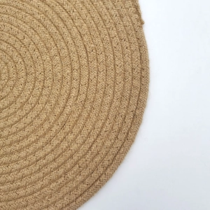 Thick round jute woven placemat in natural brown fiber with spiral pattern and heat resistance