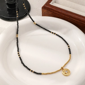 Detail of beaded necklace with black faceted beads and gold Evil Eye zircon pendant
