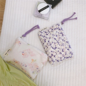 Close-up of floral fabric mini pouches with purple drawstrings and zipper closure