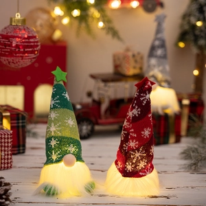 Close-up of glowing Christmas gnomes with red and green knitted snowflake hats