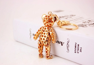 Close-up of golden bear keychain with hollow design and crystal accents on a white book