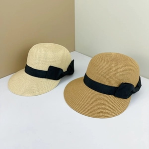 Detailed weave texture of two flat top straw hats with elegant black ribbon bows